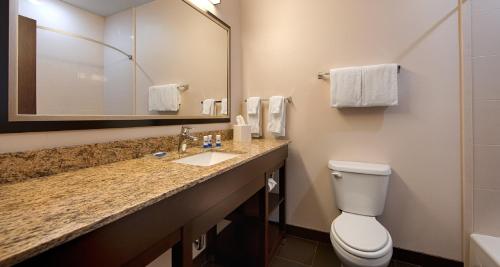 a bathroom with a toilet and a sink and a mirror at Best Western PLUS Casper Inn & Suites in Casper