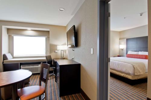 a hotel room with a bed and a desk with a table at Best Western Plus Woodstock Inn & Suites in Woodstock