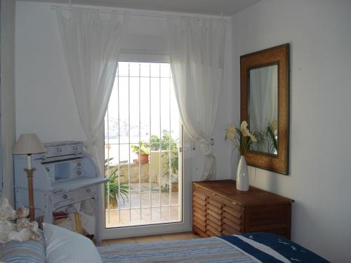 a bedroom with a bed and a mirror and a window at Ard Na Mar in Peniscola