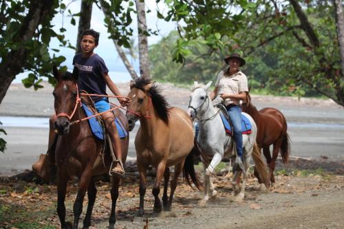 two men riding horses on a dirt road at Cafe de la Suerte in Pavones