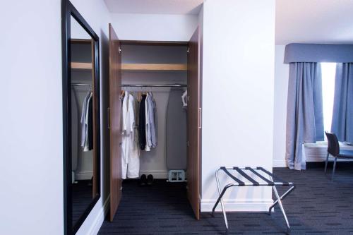 a walk in closet with a mirror and a chair at Hôtel Albert par G5 in Rouyn