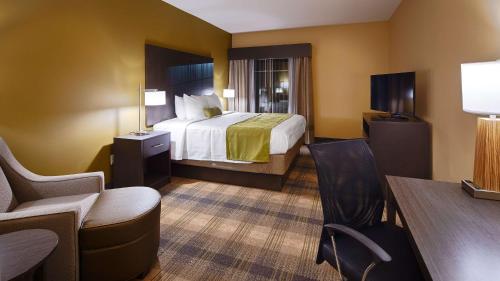 a hotel room with a bed and a table and chairs at Best Western Plus New Orleans Airport Hotel in Kenner