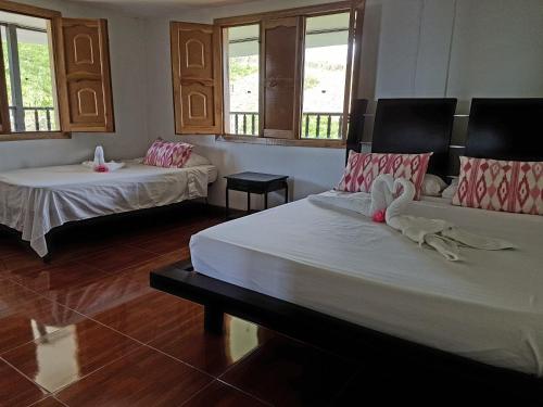two beds in a room with windows at Alojamiento Rural Bellavista in Filandia