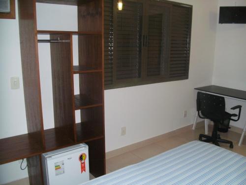 a bedroom with a bed and a book shelf and a desk at Pousada Jaó in Goiânia