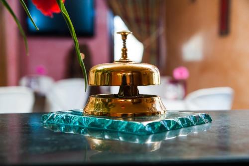 a gold bell sitting on a table with a flower at Hotel Al Ritrovo in Piazza Armerina