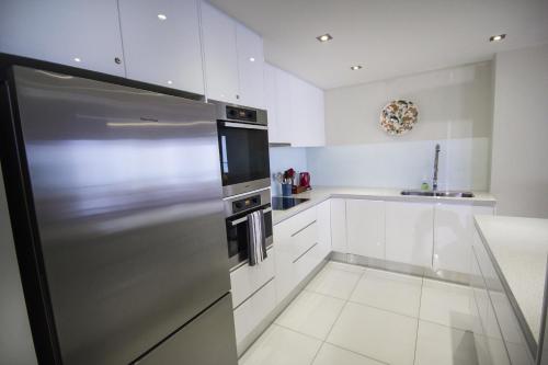 a kitchen with white cabinets and a stainless steel refrigerator at Albatross North Apartments in Gold Coast