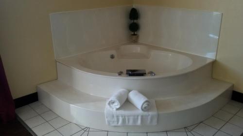 GrandStay Hotel and Suite Waseca في Waseca: حوض استحمام أبيض مع منشفتين في الحمام