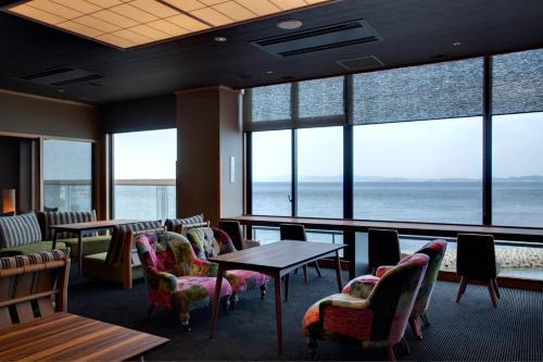 a restaurant with tables and chairs and a view of the ocean at Hanagoyomi in Sumoto