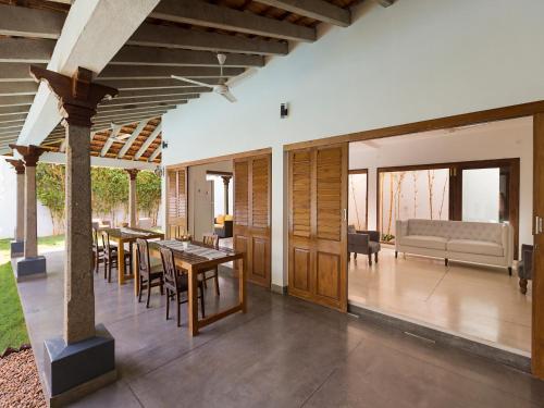 an open patio with tables and chairs and a couch at Kadal The Beach House in Puducherry