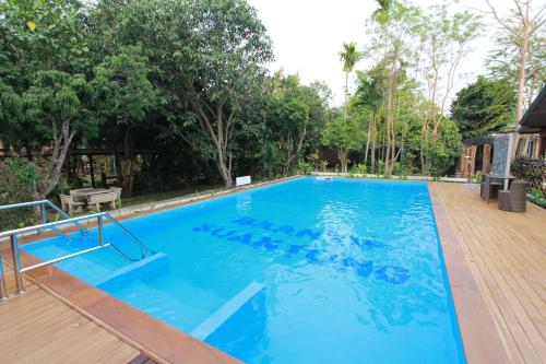 a large blue swimming pool with trees in the background at Baantip Suantong in Amphawa