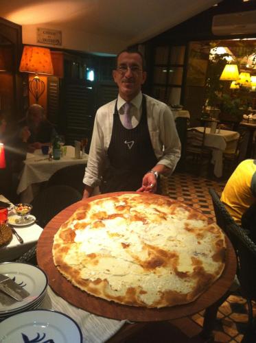 a man standing next to a large pizza on a table at Da ö Vittorio SRL in Recco