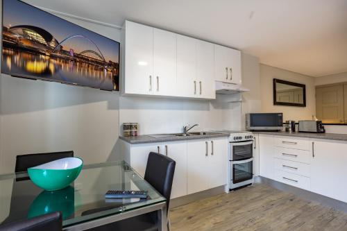 a kitchen with white cabinets and a glass table at Hamilton on Beaumont in Newcastle