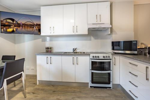 a kitchen with white cabinets and a stove at Hamilton on Beaumont in Newcastle