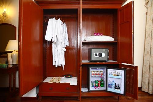 a wooden cabinet with a refrigerator in a room at Hotel Continental Saigon in Ho Chi Minh City