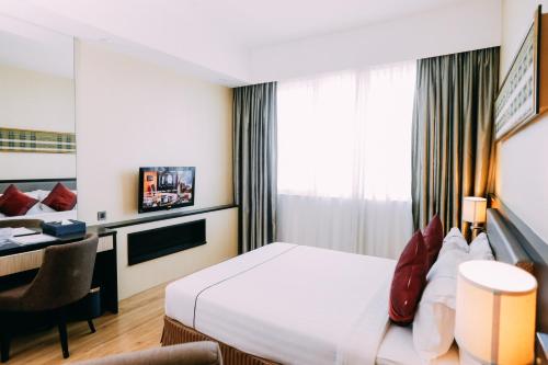 a hotel room with a bed and a desk at Hotel Granada Johor Bahru in Johor Bahru