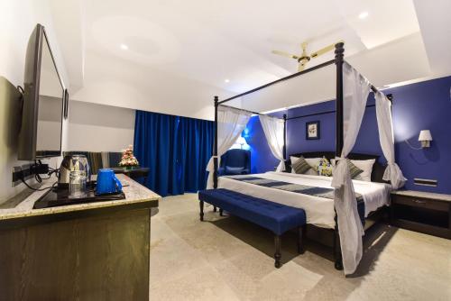 a bedroom with a canopy bed with a blue wall at Silver Sands Serenity in Candolim