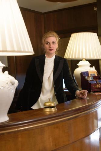 a woman standing behind a desk with a lamp at Hotel Morchio Mhotelsgroup in Diano Marina