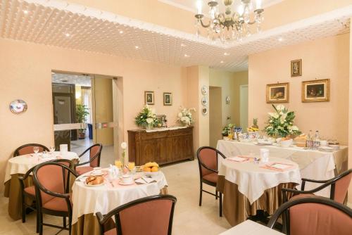 a dining room with tables and chairs and a chandelier at Hotel Morchio Mhotelsgroup in Diano Marina