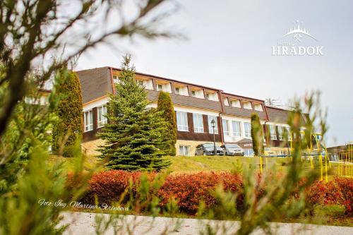 un edificio con un árbol delante de él en Hotel Hrádok, en Jelšava