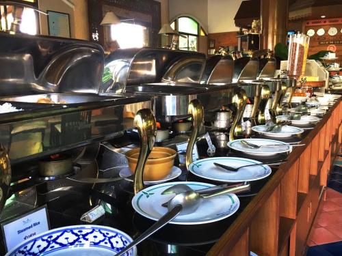 Una línea de buffet con platos y utensilios en Diana Garden Resort - SHA Extra Plus, en Pattaya central