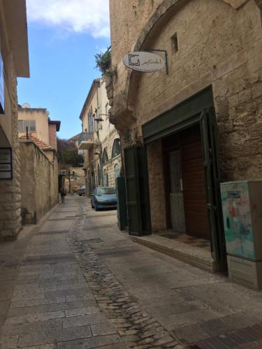an alley with a building with a sign on it at Al-Hakim Boutique Hotel Old Town Nazareth in Nazareth