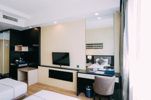 a room with a bed and a desk with a television at Hotel Granada Johor Bahru in Johor Bahru