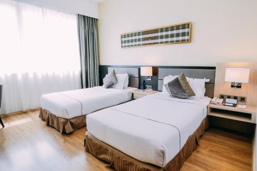 a hotel room with two beds and a desk at Hotel Granada Johor Bahru in Johor Bahru