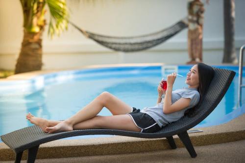 a woman sitting in a chair next to a swimming pool at Coconut Palms in Kantharawichai