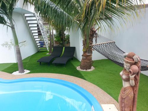 a resort with a hammock and a pool with palm trees at Coconut Palms in Kantharawichai
