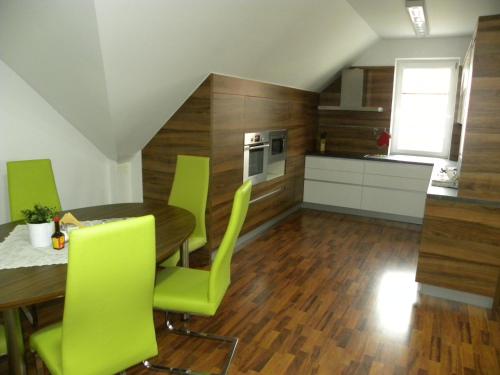 a kitchen with a wooden table and green chairs at Apartment WELLNESS Vlčková in Vlčková