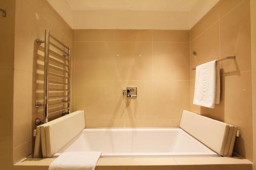a bathroom with a large tub and a shower at The Dostyk Hotel in Almaty