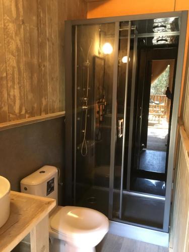 a bathroom with a toilet and a glass shower at Glamping Lodge Estartit in L'Estartit