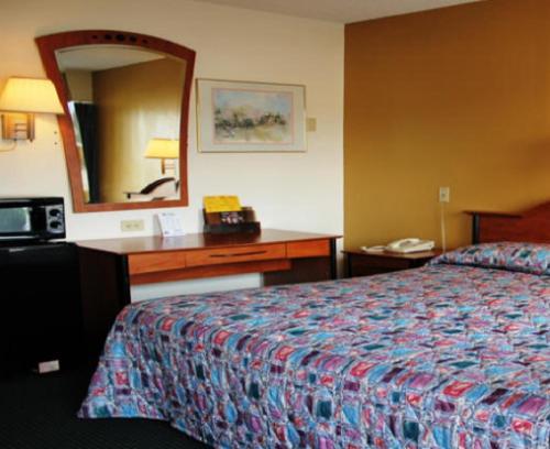Cette chambre comprend un lit et un bureau avec un miroir. dans l'établissement Speedway Inn, à Bristol
