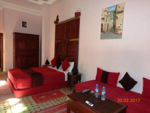 a bedroom with a red bed and a couch at Riad Ahlam in Fès