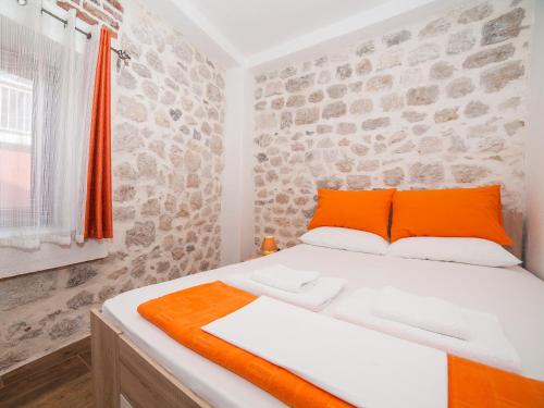 łóżko z pomarańczowymi i białymi poduszkami w pokoju w obiekcie Apartments Ana w Kotorze