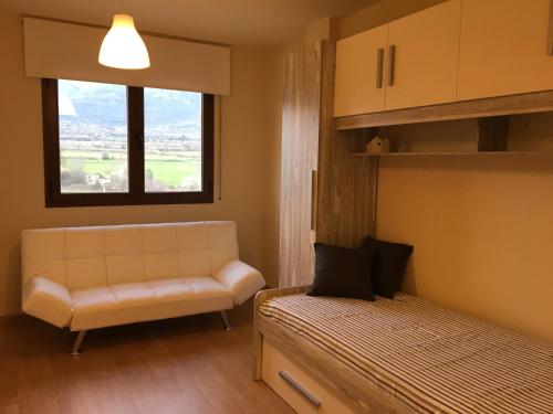 Habitación pequeña con sofá y ventana en Apartament Vall d'Àger en Ager