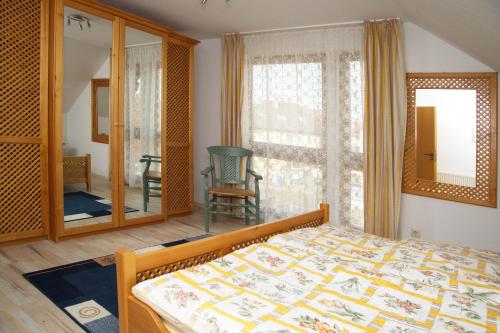 Schlafzimmer mit einem Bett und einem Fenster mit einem Stuhl in der Unterkunft Ferienhaus Bauerngarten in Bad Buchau