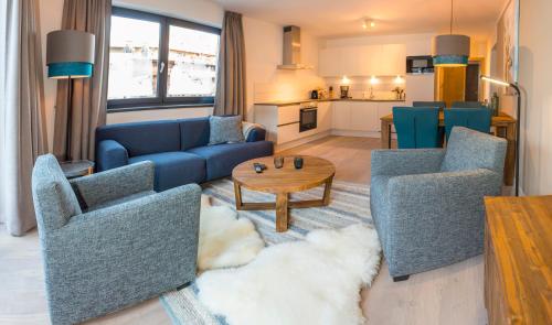 a living room with blue couches and a table at Kristall Plaza in Niederau