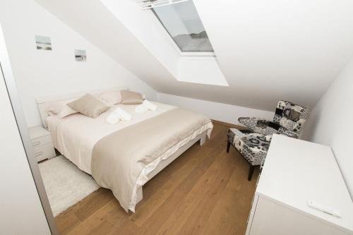 a white bedroom with a bed and a chair at LCT Apartment Laura in Omiš