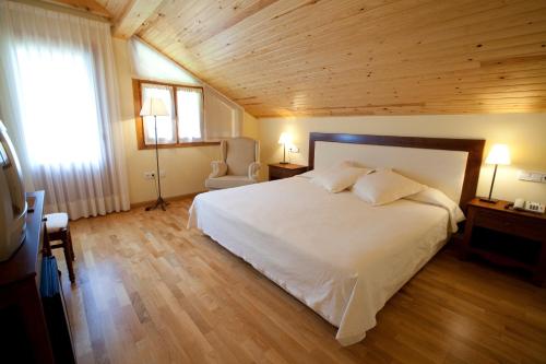 a bedroom with a white bed and a wooden ceiling at Hotel Estanys Blaus in Tavascan