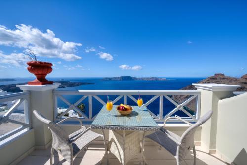 a table on a balcony with a view of the ocean at Ellinon Thea Boutique Hotel in Firostefani