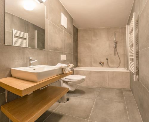 a bathroom with a sink and a toilet and a tub at Kristall Plaza in Niederau