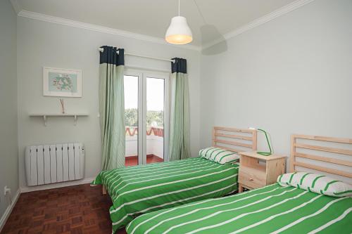 エリセイラにあるEriceira Atlantic Ocean Hill Apartmentの緑と白のシーツが備わるベッドルームのベッド2台