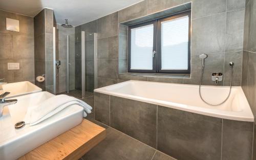 a bathroom with a tub and a sink at Kristall Plaza in Niederau