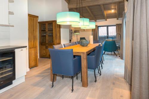 a dining room with a wooden table and blue chairs at Kristall Plaza in Niederau