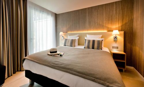 a bedroom with a large bed with a hat on it at Golden Tulip Sophia Antipolis - Hotel & Spa in Valbonne