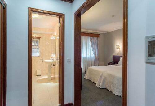 a bedroom with a bed and a bathroom with a mirror at Hotel Boavista II in Melgaço