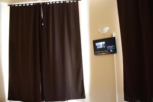 a bathroom with a curtain and a television on a wall at Hotel Sansa in Maastricht