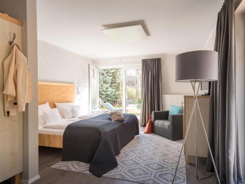 a bedroom with a bed and a chair and a lamp at Bodenseehotel Renn in Hagnau