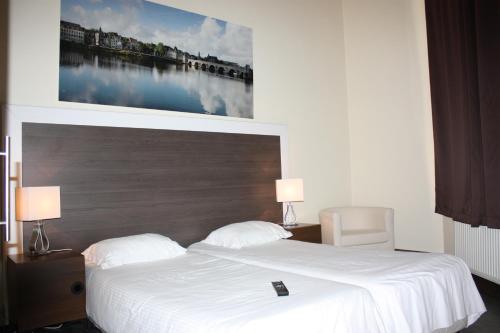 a bedroom with a white bed with a picture on the wall at Hotel Sansa in Maastricht
